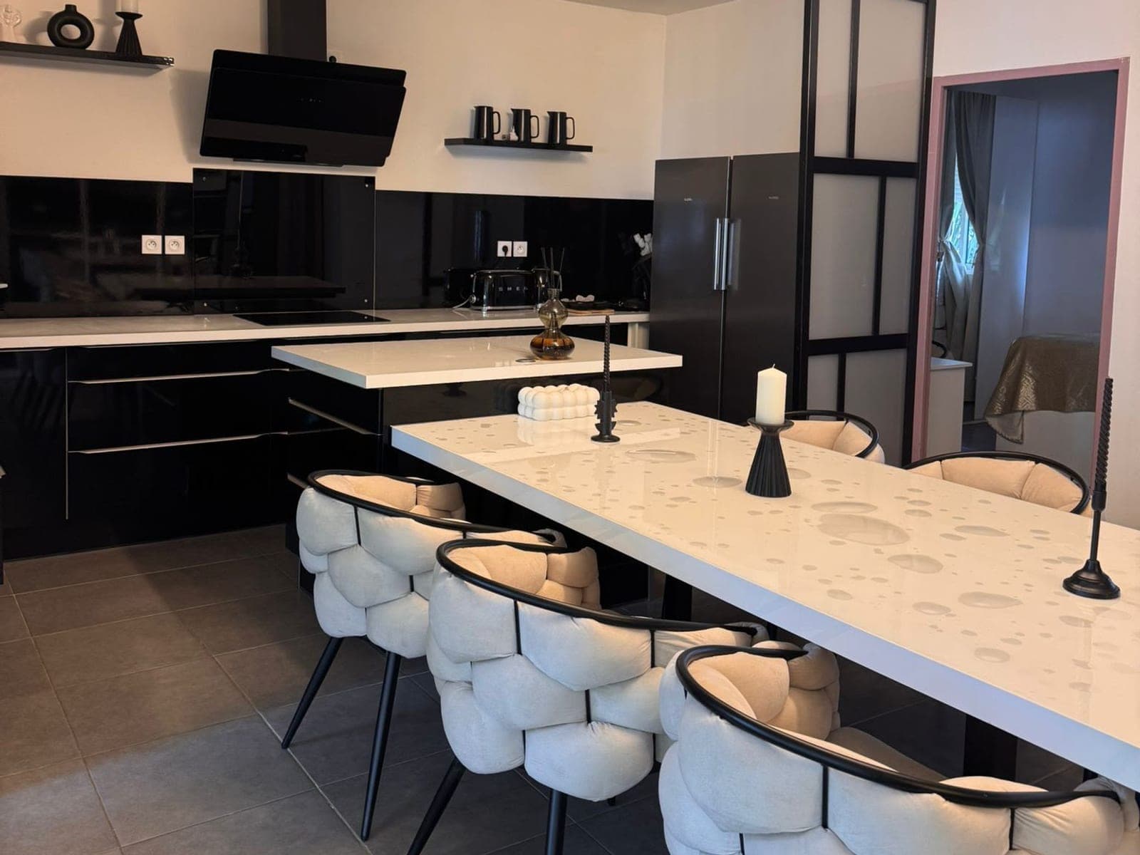 Cuisine ouverte et grande table blanche d'un logement meublé, rangés et prêts pour une visite