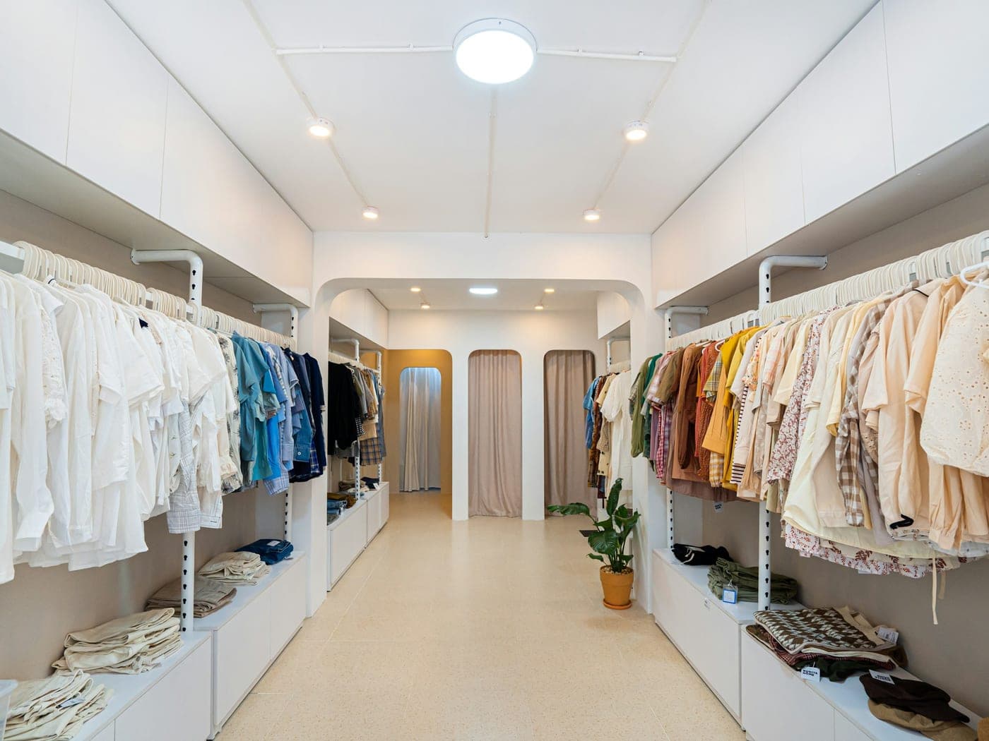Boutique de vêtements vide, portants alignés, sol clair