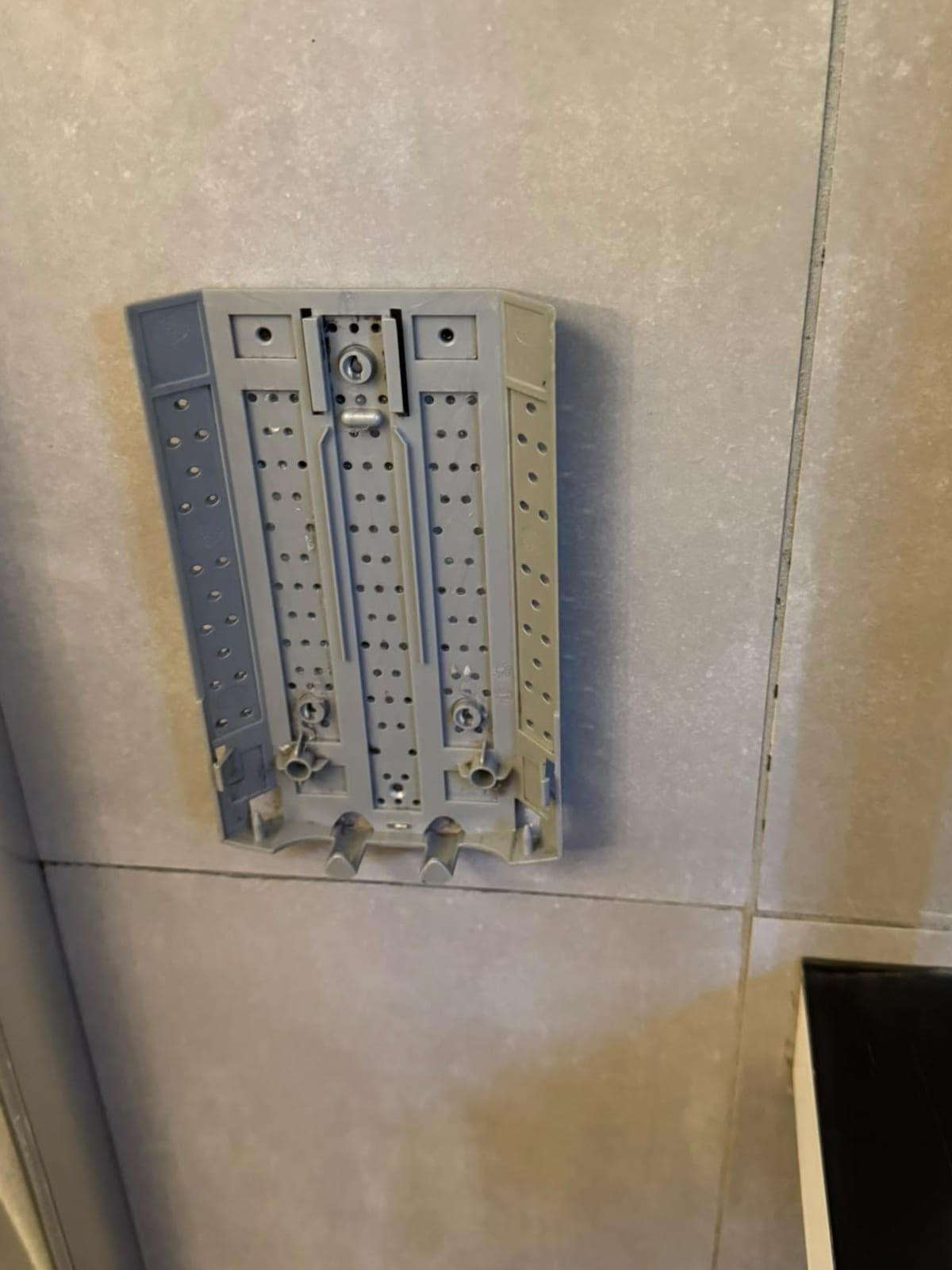 Support mural gris d'un distributeur de douche, propre, sur carrelage