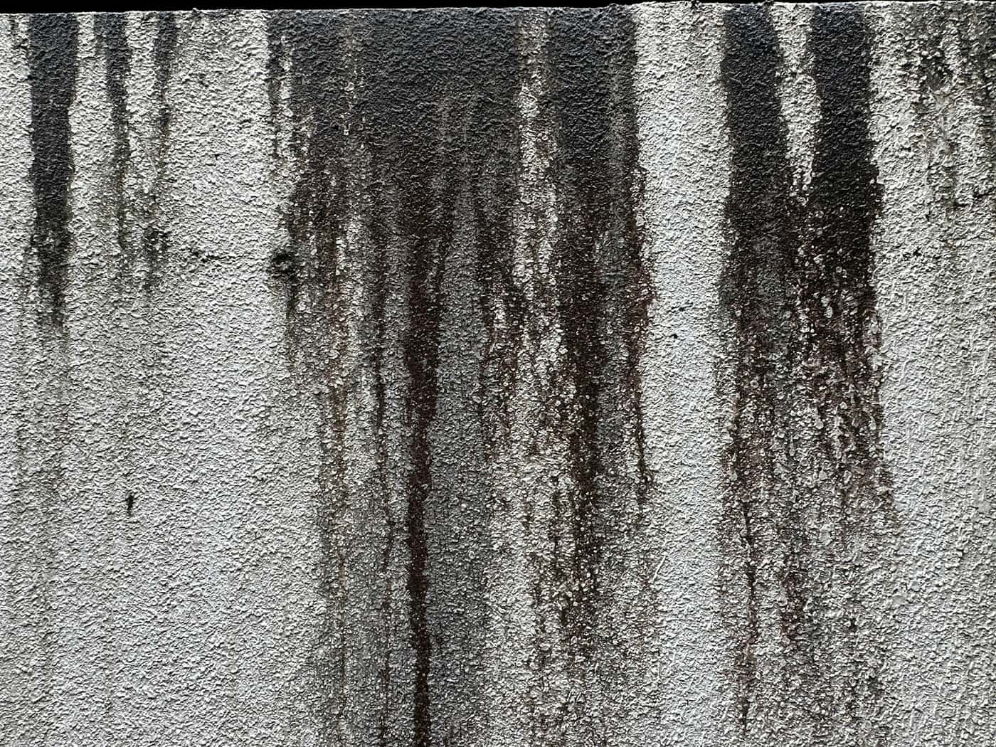 Traces sombres de suie qui coulent sur un mur clair