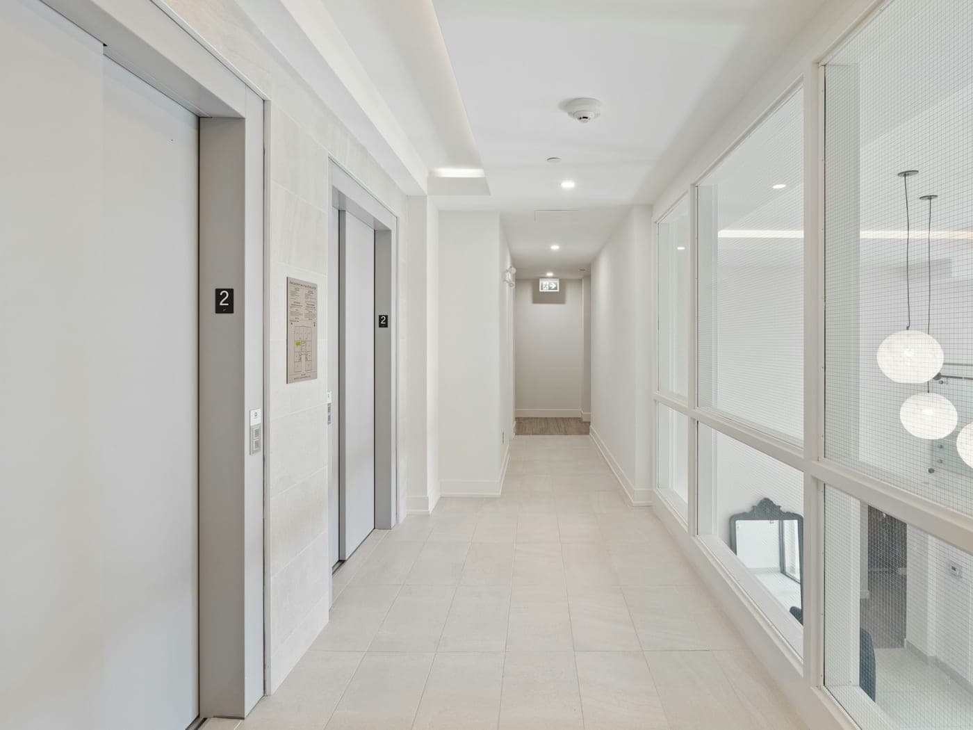 Couloir d'immeuble carrelé avec ascenseurs, propre et clair
