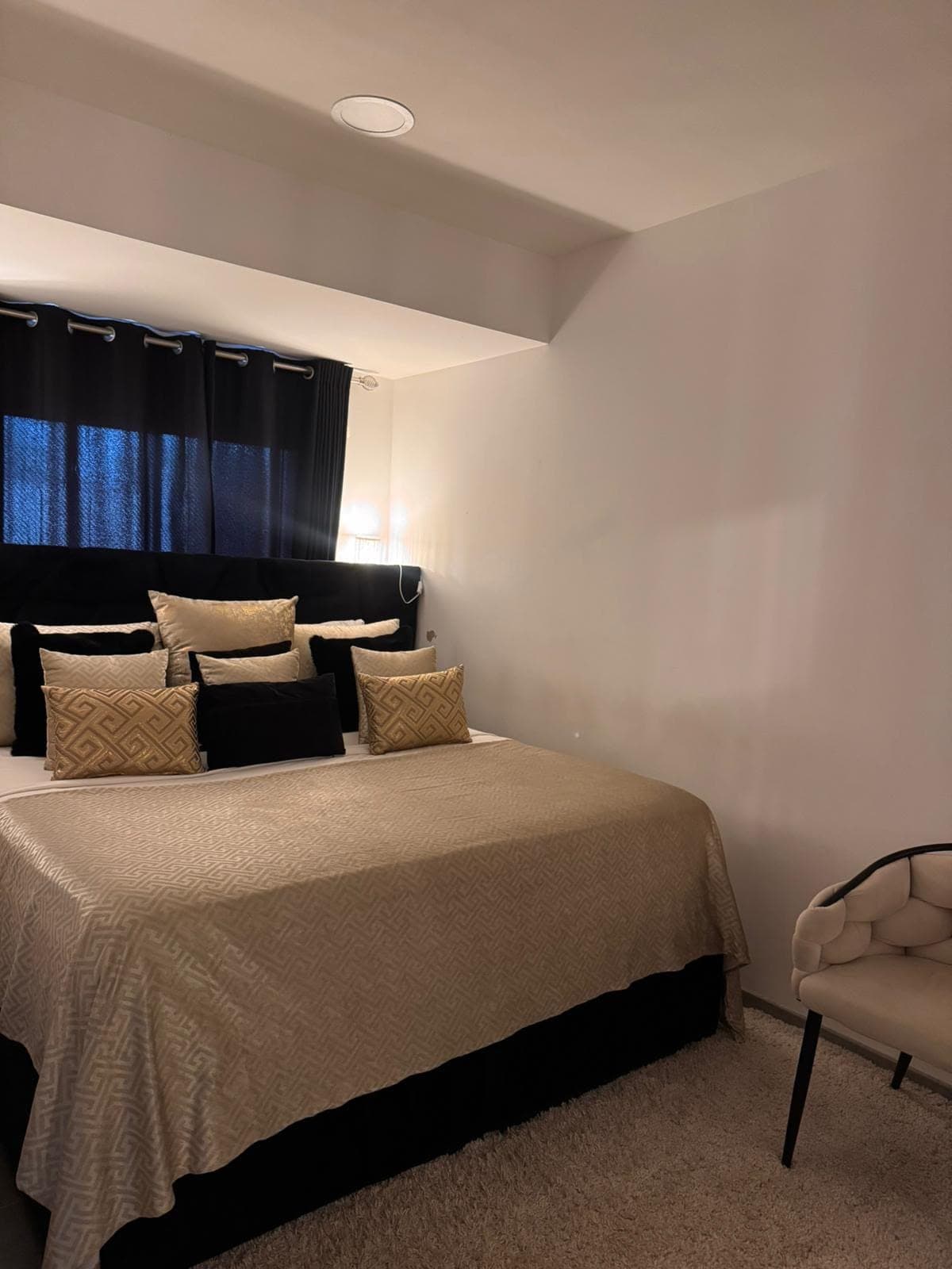 Chambre au lit fait, coussins noirs et dorés alignés