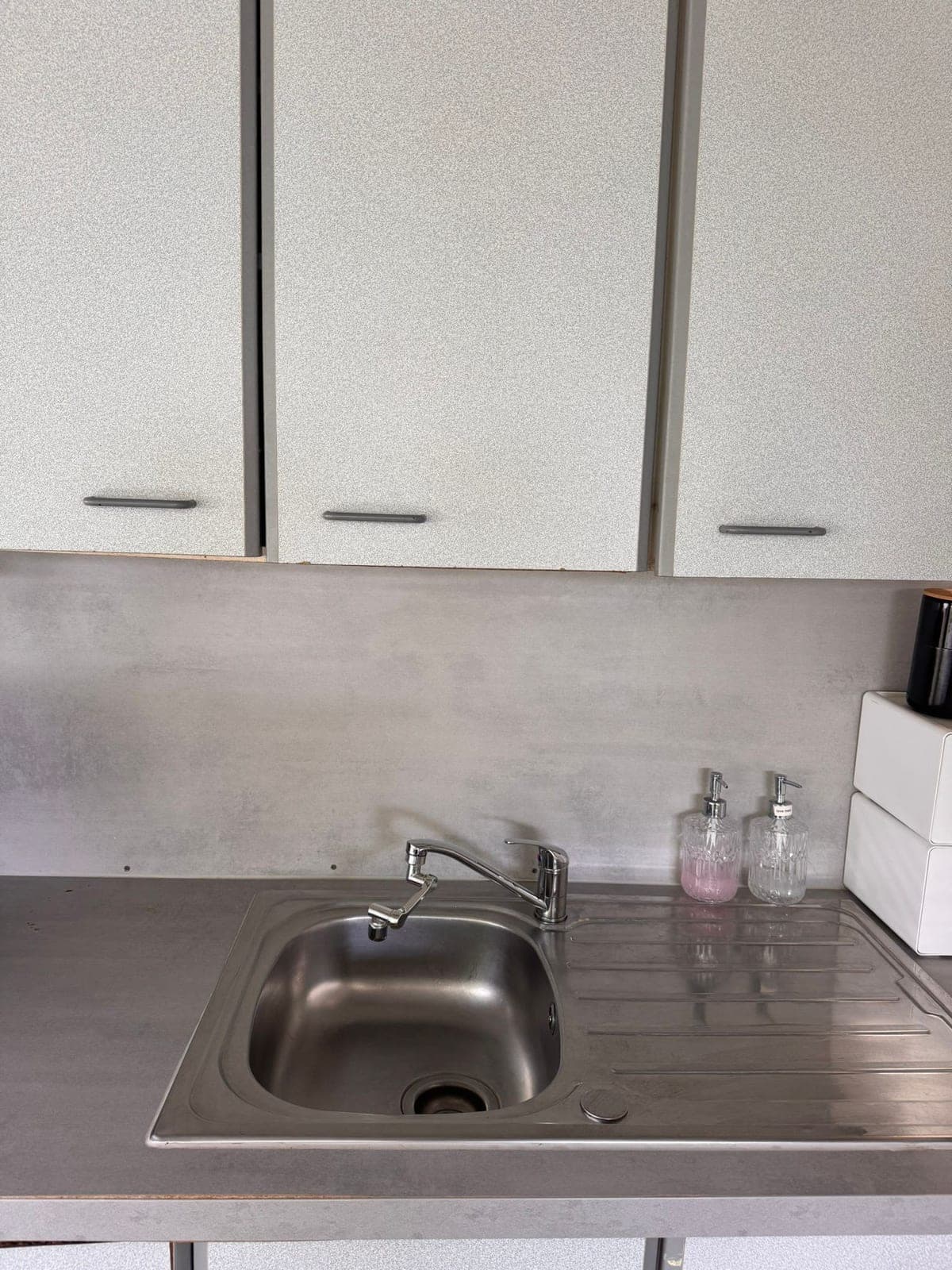 Évier en inox et égouttoir propres sous des placards blancs