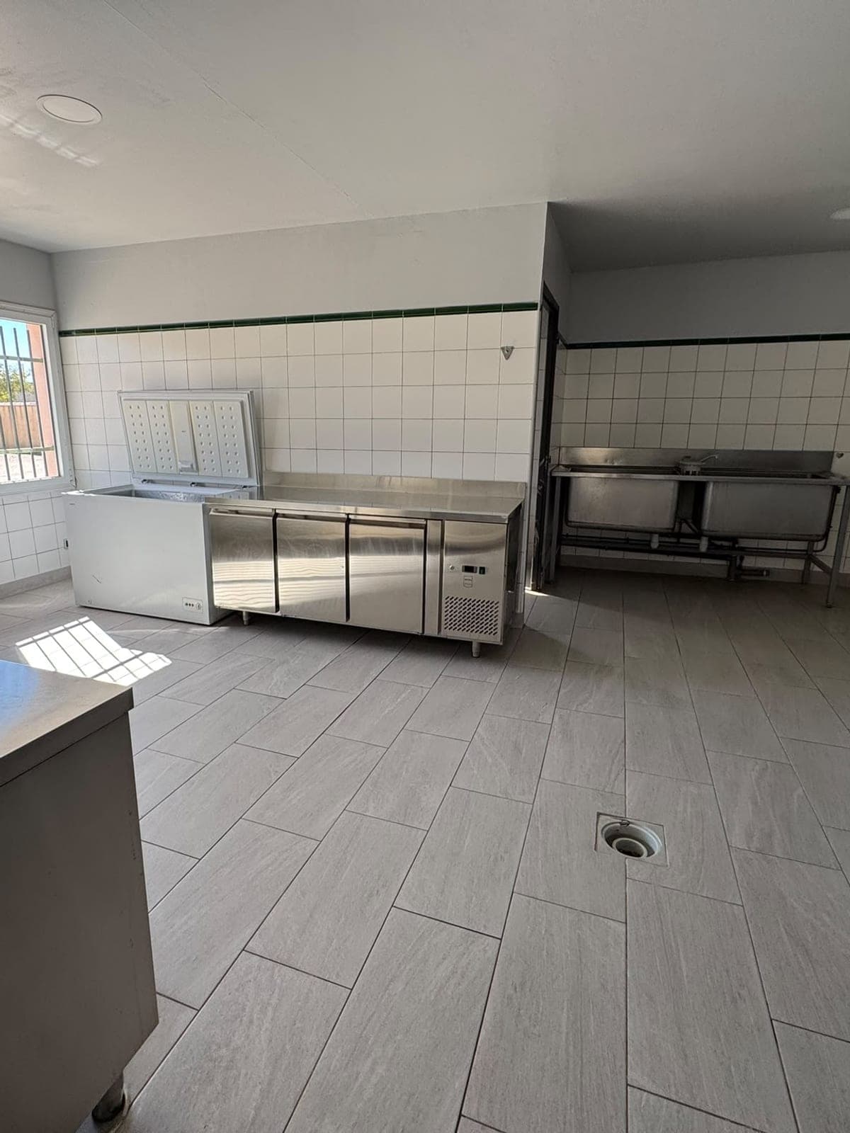 Cuisine professionnelle au carrelage blanc, meubles inox et sol lavé
